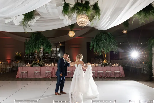 Wedding couple dancing on the glossy all-white paneled floor at Waypoint 4180 beneath draping and greenery