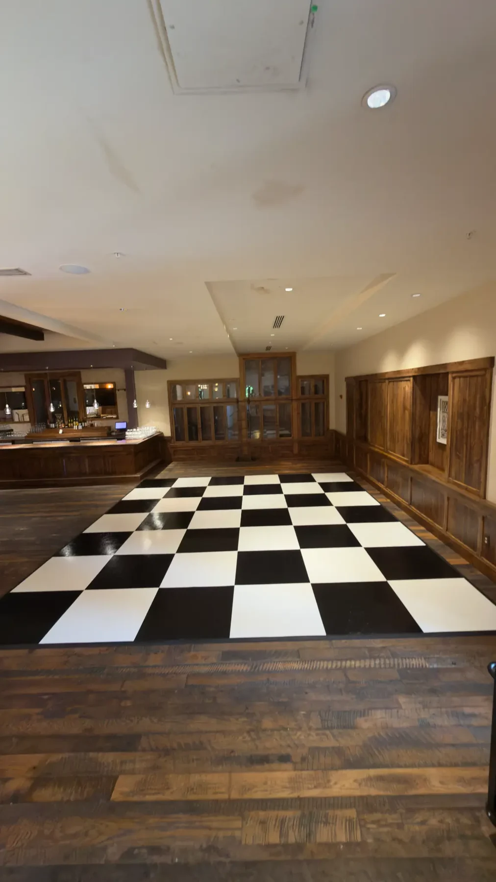 Real black-and-white checkerboard dance floor in a warm wood-paneled event space