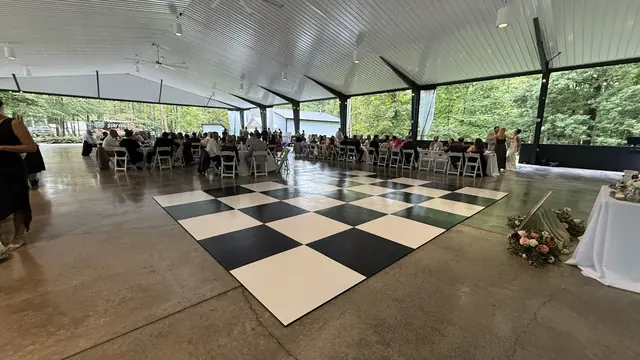 Real checkerboard dance floor surrounded by reception tables in an open-sided pavilion