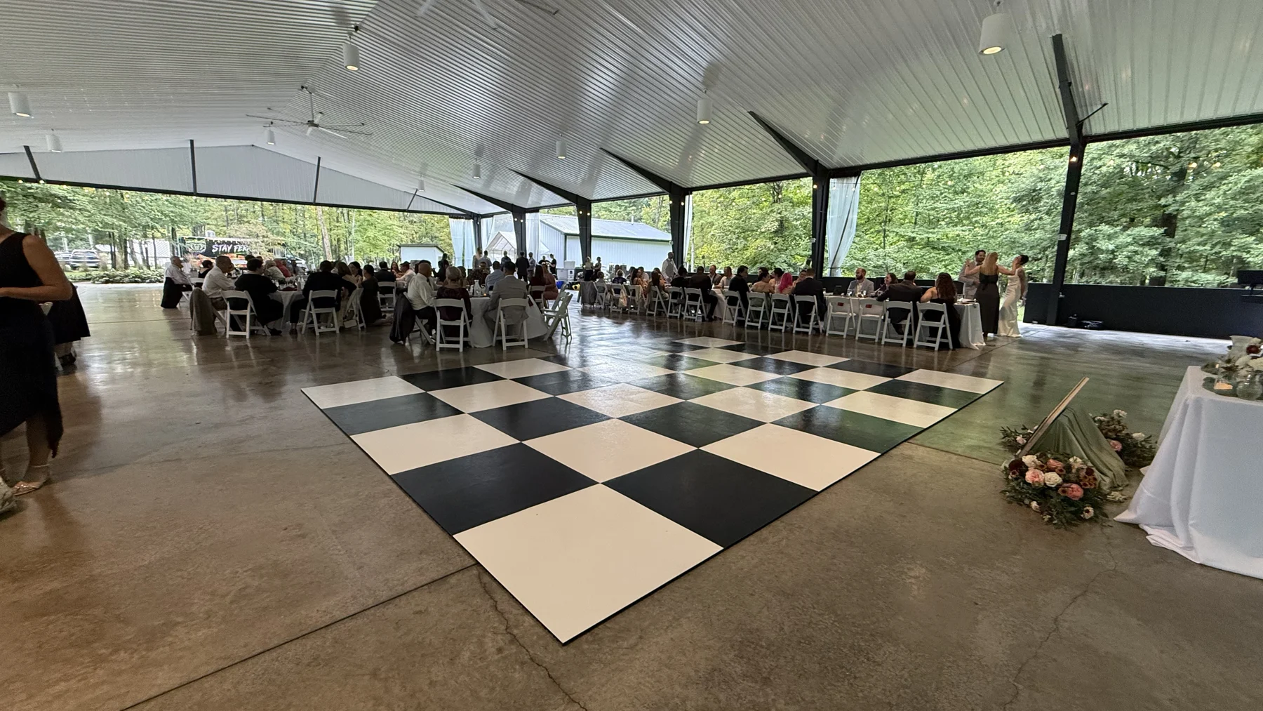 Real checkerboard dance floor surrounded by reception tables in an open-sided pavilion