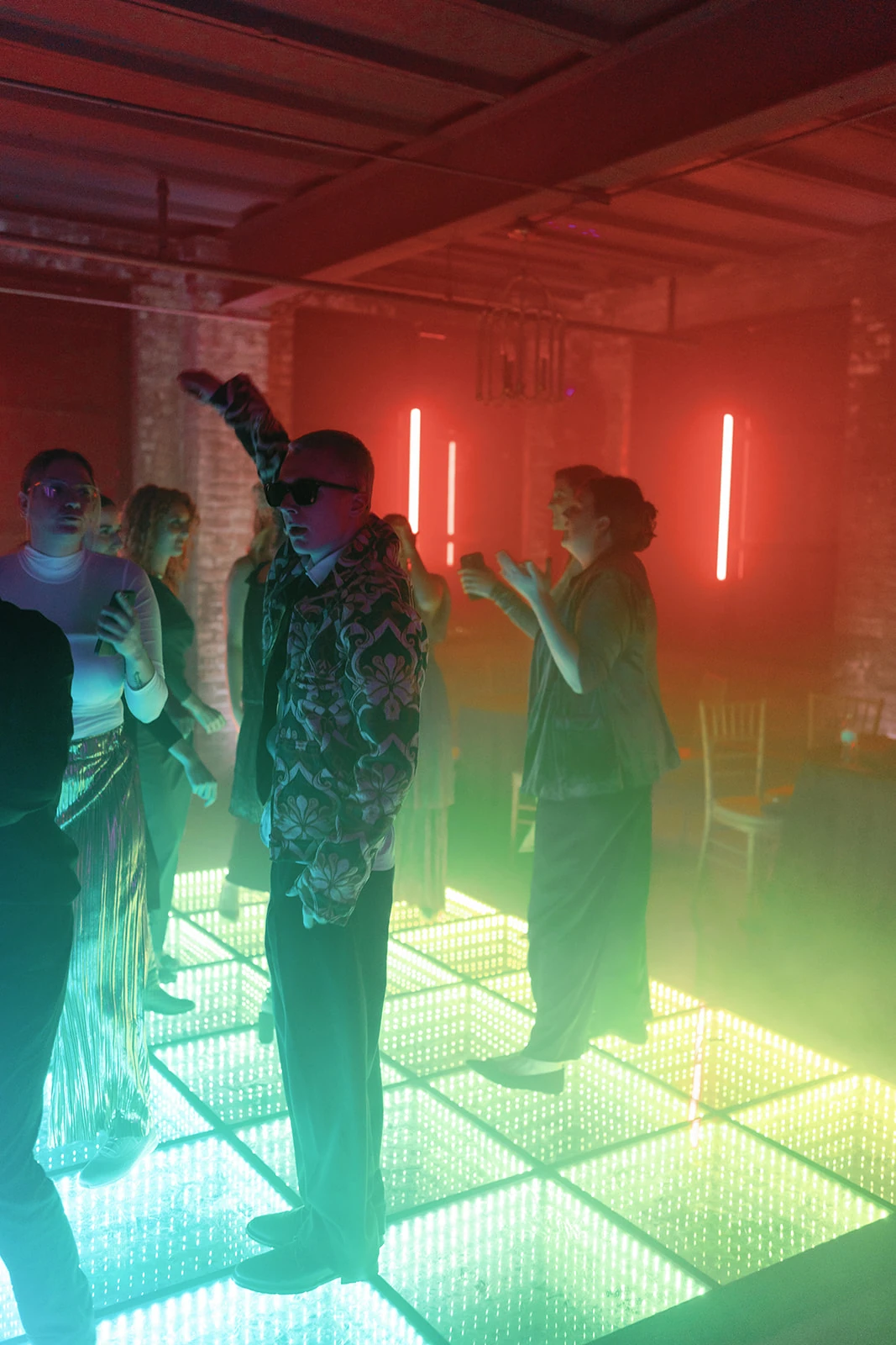 Guests standing on mirrored LED panels with green, yellow and aqua lights